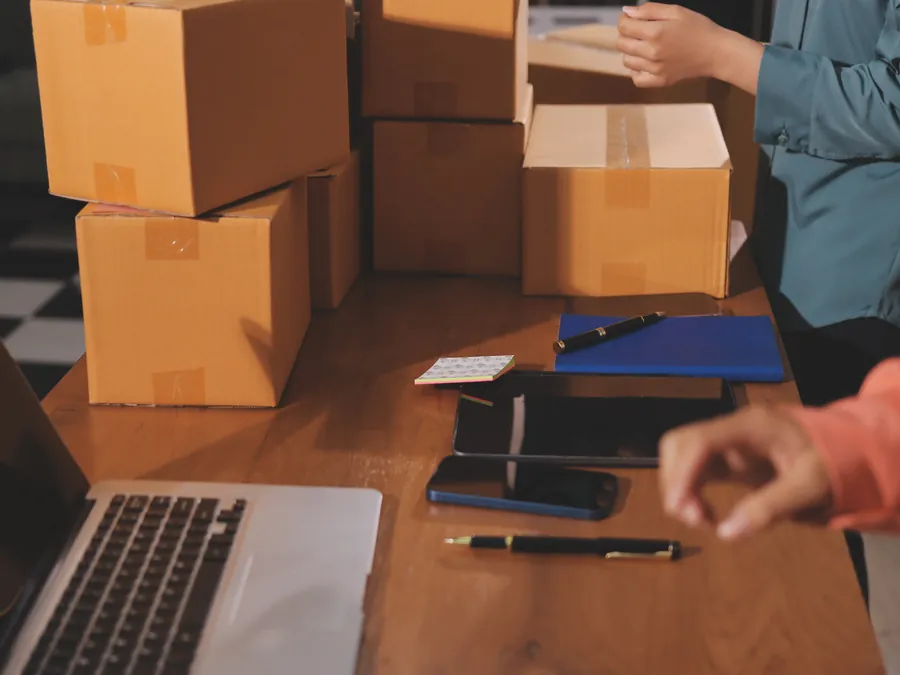 Packing station with cartons, a laptop and order documents