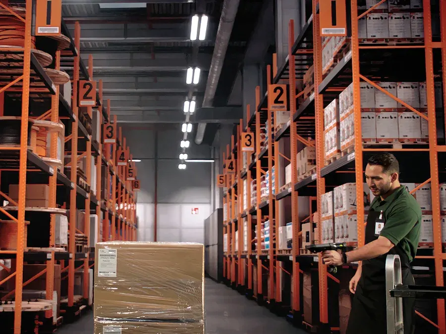 Picker with a handheld scanner in a warehouse aisle next to a pallet