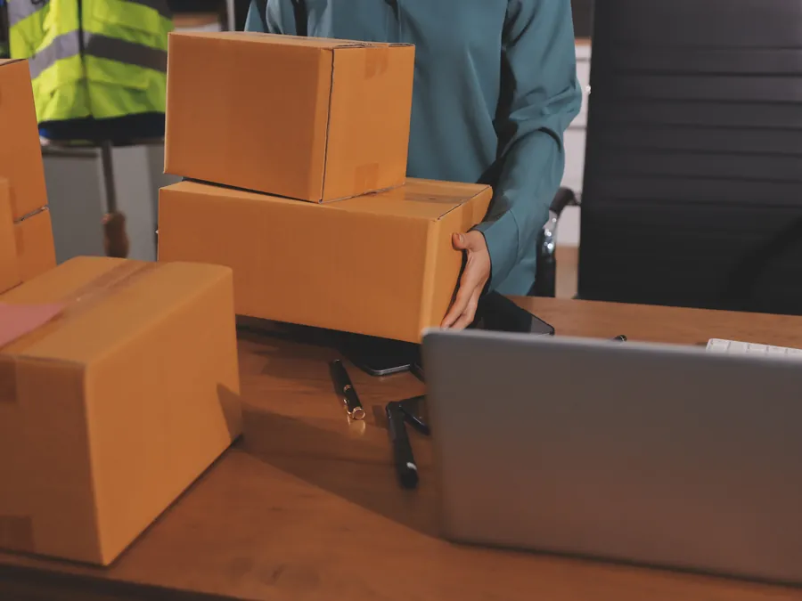 Warehouse staff preparing parcels and checking orders on a laptop