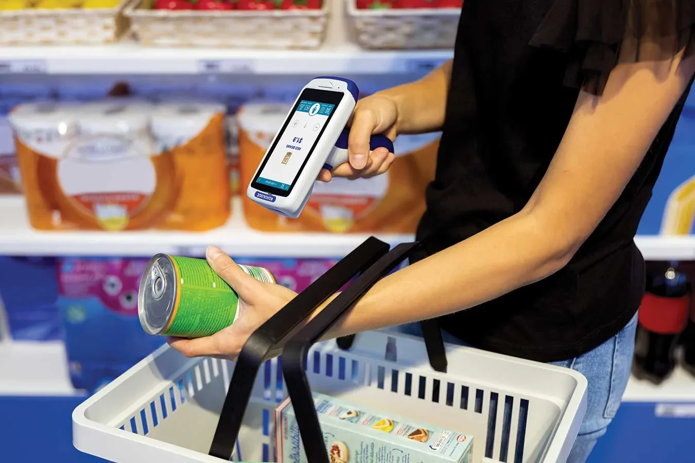 Shopper scanning a grocery product while holding a shopping basket.