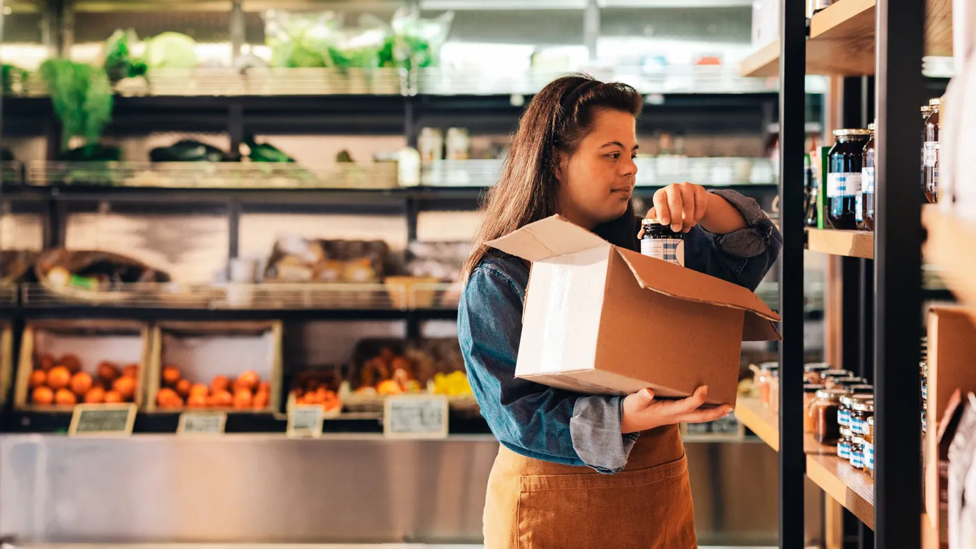 Store worker counting stock with a box in hand